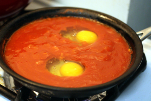 Two eggs just after being dropped into a bubbling pan of tomato sauce